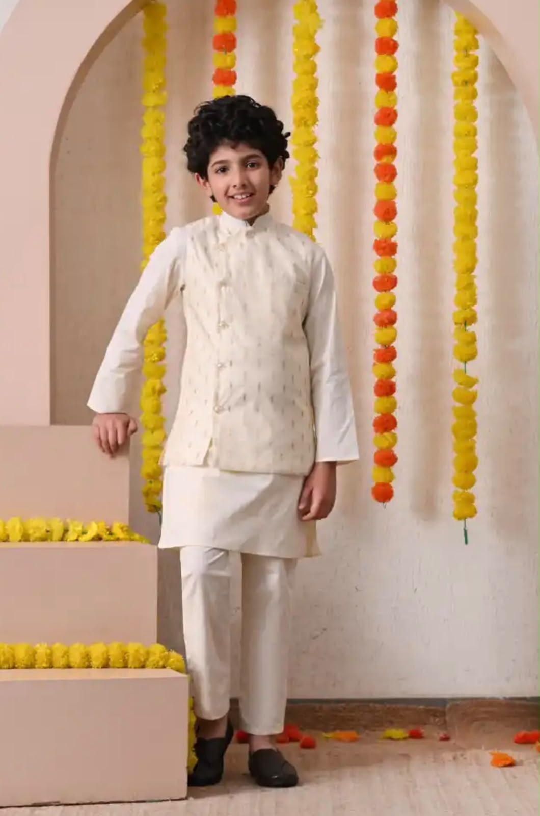 Smiling boy in a golden buti-print festive kurta pyjama set with jacket